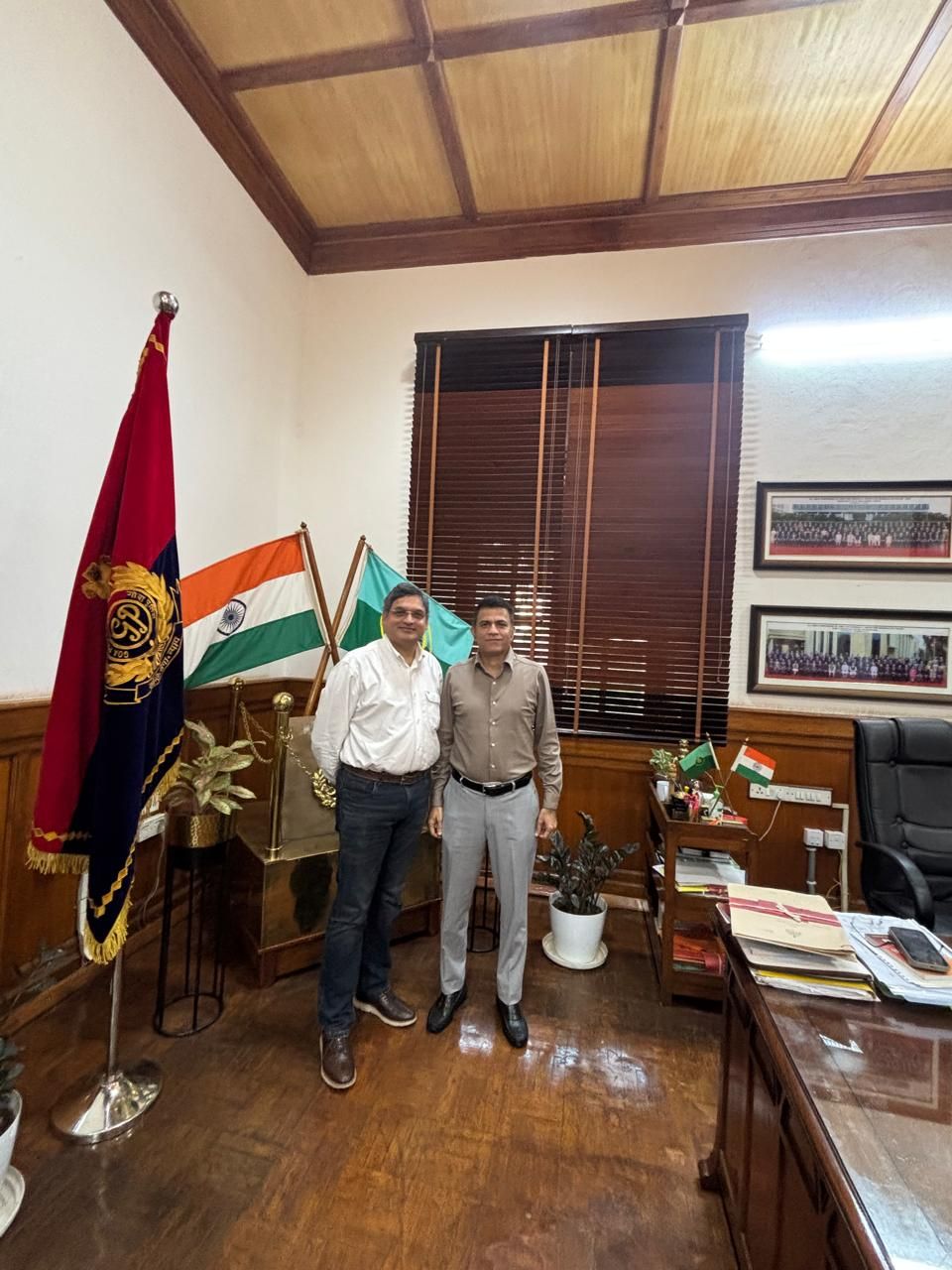 Alok Kumar and Prashant Nikam standing together in an office, with the Indian flag and a police flag behind them, and framed pictures on the wall.