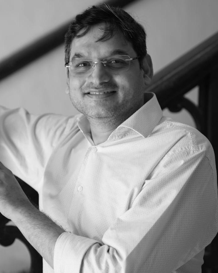 Prashant Nikam, in a white shirt, leaning on a carved wooden banister.